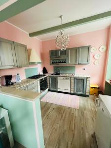 Una cocina con paredes rosas y suelos de madera y una lámpara de araña. en Thea House, en Casale Monferrato