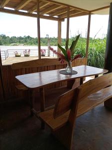 una mesa de madera con un jarrón de flores y dos bancos en River Spot Lodge, en Tena