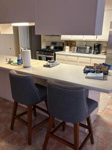 una cocina con un gran mostrador blanco con 2 sillas en Rare four Bedroom MeadviewVacation Home - Grand Canyon West-Skywalk, en Meadview