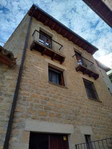 - un grand bâtiment en briques avec des fenêtres et un balcon dans l'établissement Casona Rey Fernando, à Sos del Rey Católico