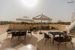 a patio with tables and chairs and umbrellas at Pyramids Golden Gate Hotel - Full Pyramids View & Roof Top in Cairo