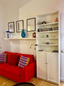 een woonkamer met een rode bank en een boekenplank bij la casa di Romolo in Rome