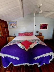 Una cama con una manta púrpura y almohadas. en Casa del Paso en Bolulla