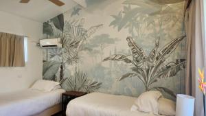 a bedroom with two beds and a tropical wallpaper at Hotel Cocoplum Beach in San Andrés