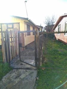 a fence with a gate in front of a house at Cabaña interior 4 personas in Quellón