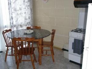 une cuisine avec une table, des chaises et une cuisinière dans l'établissement Attard Seafront Apartment 3 in Marsalforn, à Żebbuġ