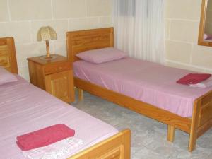 une chambre avec deux lits et une table de nuit avec une lampe dans l'établissement Attard Seafront Apartment 3 in Marsalforn, à Żebbuġ 5 autres photos