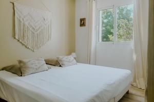 Cama blanca en habitación con ventana en LA VILLA ALBA en Les Issambres