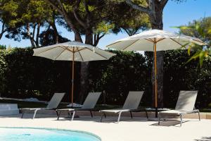 twee parasols en ligstoelen naast een zwembad bij LA VILLA ALBA in Les Issambres