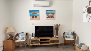 a living room with a television and two chairs at Cristal House 250 meters from Monte Gordo beach in Monte Gordo