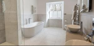 La salle de bains blanche est pourvue d'une baignoire et d'un lavabo. dans l'établissement Storrs Hall Hotel, à Bowness-on-Windermere