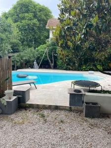 a swimming pool with two tables and benches next to it at Bas de villa avec grande piscine in Marseille