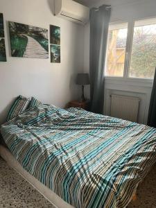 a bedroom with a bed with a colorful comforter and a window at Bas de villa avec grande piscine in Marseille