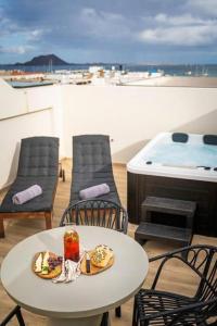 una mesa con un plato de comida en la parte superior de un balcón en Jable suites apartamentos de lujo en el centro en Corralejo