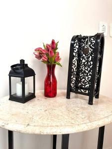 a table with a red vase with flowers and a lantern at Fique no Centro de Petrolina in Petrolina