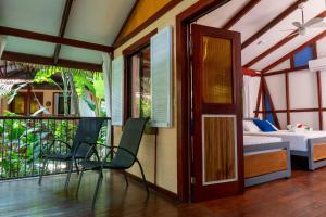 Zimmer mit einem Balkon mit einem Bett und Stühlen in der Unterkunft Namuwoki Lodge in Puerto Viejo