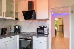 La cuisine est équipée de placards blancs et d'un four micro-ondes. dans l'établissement Mega Lux Apartment, à Esslingen am Neckar