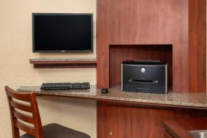 um quarto com uma secretária, um computador e uma televisão em Days Inn by Wyndham Rockford em Rockford