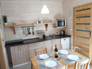 eine Küche mit einem Tisch und Stühlen sowie eine Küche mit einem Waschbecken in der Unterkunft Domki na Leśnej in Ustronie Morskie