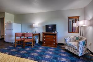 a living room with a chair a table and a refrigerator at All Towne Suites in Saint Robert