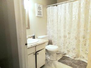 a bathroom with a toilet and a shower curtain at Cheeful, 2bed x 1bath Brick House in New Orleans +19 photos