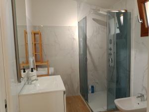 uma casa de banho branca com um chuveiro e um lavatório. em La Grotta em Urzulei