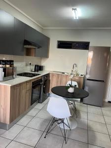 a kitchen with a black table and a white chair at The Lagoon Exquisite Apartments in Pretoria
