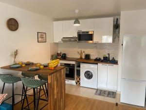a kitchen with white cabinets and a table and a refrigerator at Le Refuge Urbain in Villejuif +17 photos