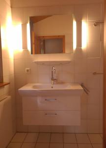 a white bathroom with a sink and a mirror at Haus Reihernest in Sehestedt