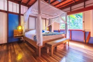 a bedroom with a canopy bed and a wooden floor at Namuwoki Lodge in Puerto Viejo