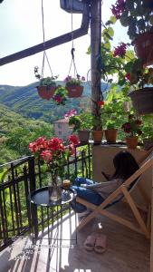 una donna seduta su una sedia su un balcone con fiori di Cherqe Guest House a Sighnaghi