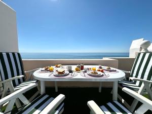 uma mesa com comida e cadeiras numa varanda com o oceano em Diletta Beach Estepona em Estepona