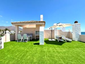 埃斯特波納的住宿－Diletta Beach Estepona，庭院设有草坪、椅子和遮阳伞