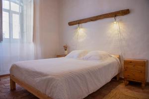 a bedroom with a white bed with a wooden headboard at Casa da Portela, Algarve Tradicional - Geoparque Algarvensis in São Bartolomeu de Messines