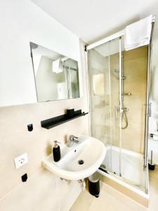 een witte badkamer met een wastafel en een douche bij StayHere Central City Studio 18 - contactless Self-Check-IN in Graz