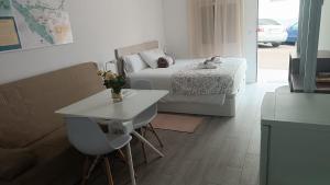 uma sala de estar com uma cama, uma mesa e um sofá em ALAUDAE APARTAMENTOS em Mérida