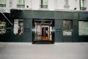 City Inn Paris في باريس: امرأة تخرج من مبنى أخضر