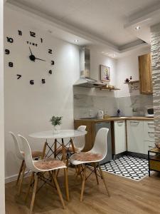 a kitchen with a table and chairs and a clock on the wall at Apartman UNA-Plandište in Bihać