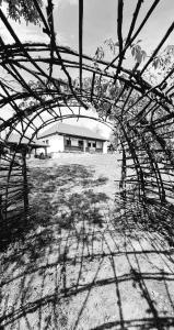 - une vue sur un bâtiment à travers une structure en bois dans l'établissement Acul în carul cu fan, à Pădurenii