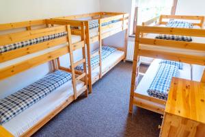 a bunk room with three bunk beds and a table at Domček Horskej Služby in Liptovská Sielnica