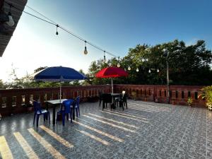 two tables and chairs with umbrellas on a patio at Hostal Casa Taisha in Montañita