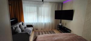ein Schlafzimmer mit einer Couch und einem Fernseher in einem Zimmer in der Unterkunft Shunja in Daugavpils