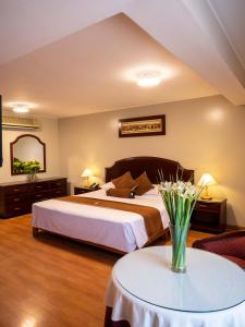 una camera d'albergo con letto e tavolo con fiori di Hotel Britania San Borja a Lima