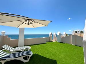 a patio with chairs and an umbrella and the ocean at Diletta Beach Estepona in Estepona
