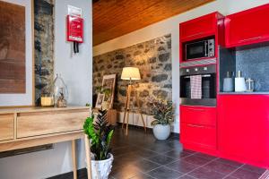 Una cocina con gabinetes rojos y un microondas. en Valley Canhas, a Home in Madeira, en Ponta do Sol