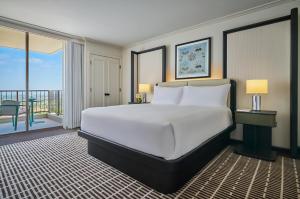 a bedroom with a large bed and a balcony at Pendry Newport Beach in Newport Beach
