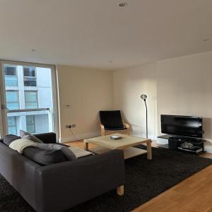 ein Wohnzimmer mit einem Sofa und einem TV in der Unterkunft Canary Wharf - Luxury Apartments in London