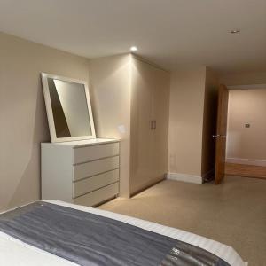 um quarto com uma cama com um espelho e uma cómoda em Canary Wharf - Luxury Apartments em Londres