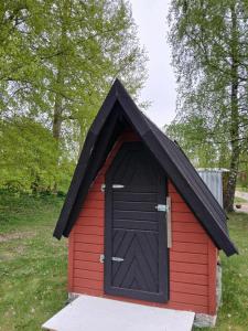 a red and black doghouse with a black door at Braås camping in Braås