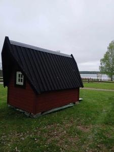 a red house with a black roof in a field at Braås camping in Braås